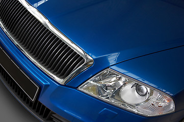 Image showing headlight and grate of radiator on a dark blue car