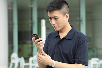 Image showing Asian man typing a message on mobile phone.