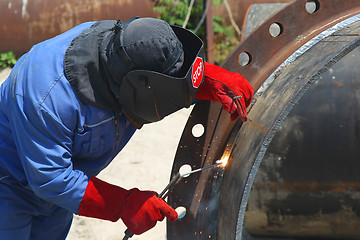 Image showing A welder working with a metal pipe