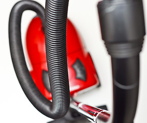 Image showing The red vacuum cleaner with a black hose on a white background
