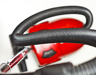 Image showing The red vacuum cleaner with a black hose on a white background
