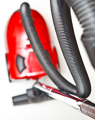 Image showing The red vacuum cleaner with a black hose on a white background
