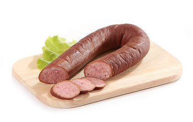 Image showing smoked sausage and lettuce on wooden cutting board