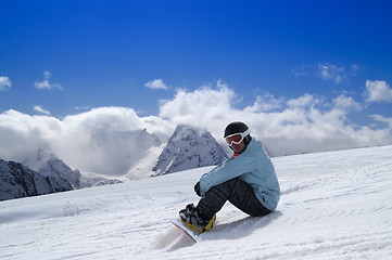 Image showing Snowboarder sitting on the snow