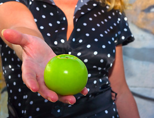 Image showing beautiful young woman holds out a green apple