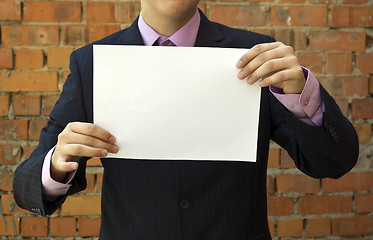 Image showing Business man holding a blank white sheet of paper