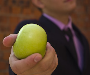 Image showing young man stretches out green apple