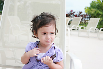 Image showing cute toddler girl in summer clothes and sunglasses lyiing on a l