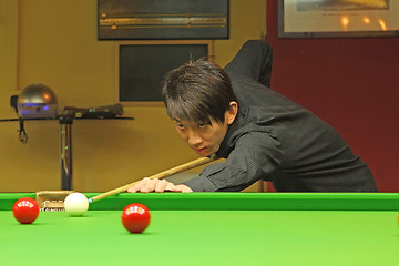 Image showing Young man concentrating while aiming at pool ball while playing 