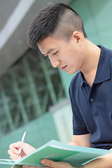 Image showing casual asian businessman texting on his book. 