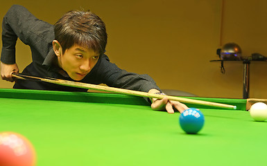 Image showing Young man concentrating while aiming at pool ball while playing 