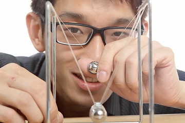 Image showing man moving Newton balls in office 