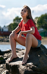 Image showing girl in a red sweater sits on a rock