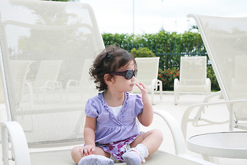 Image showing adorable young baby girl wearing sunglasses in flirting position