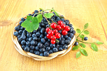 Image showing Blueberries with sprigs of red currants on the board