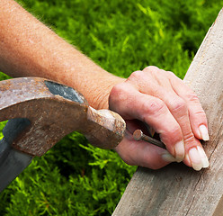 Image showing Female Hand, Hammer, Nail, Board