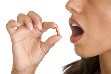 Image showing young women pops a pill into her mouth