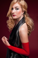 Image showing Perfect blonde in a black dress on red