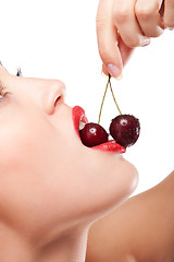 Image showing young woman's mouth with red cherries