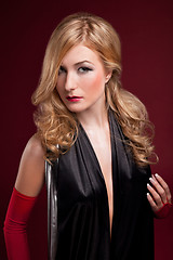 Image showing Perfect blonde in a black dress on red