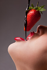 Image showing girl eating strawberry with chocolate sauc