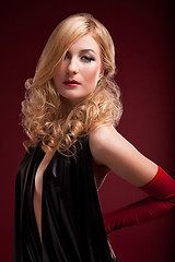 Image showing Perfect blonde in a black dress on red