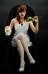 Image showing Girl sits in black chair with a rose and skull