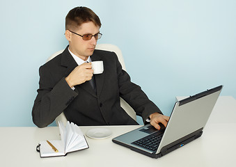 Image showing Businessman reads news online and drinking coffee