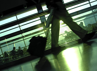 Image showing Making the Flight, An airport terminal with silhouettes of passengers waiting and one man walking.