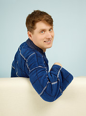 Image showing Happy smiling man sitting on couch in dressing gown