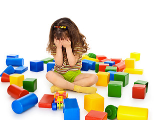 Image showing Little girl sitting on white among toys and crying