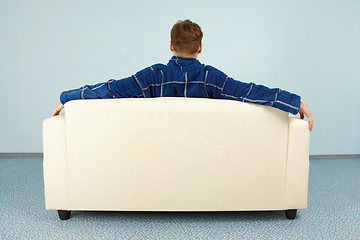 Image showing Young man sitting at home on couch