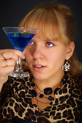 Image showing Young woman looks at glass with unusual cocktail