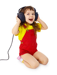 Image showing Little girl sitting on white with large earpieces