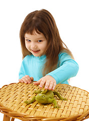 Image showing Girl cautiously stroking a toy lizard