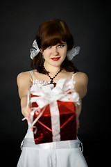 Image showing Young attractive woman gives a gift in red box