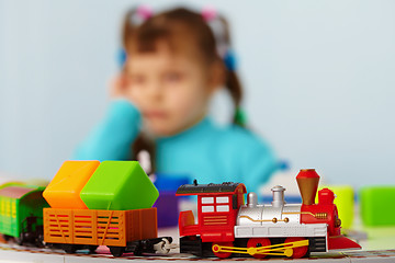 Image showing Little girl bored playing with toys alone