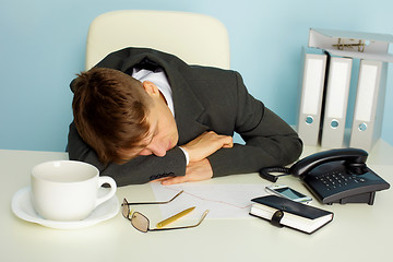 Image showing Tired man sleeping on a table
