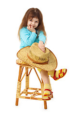 Image showing Child sits on an old wooden chair with hat