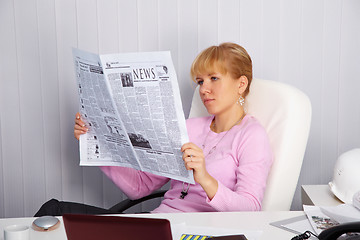 Image showing Beautiful young girl reads newspaper