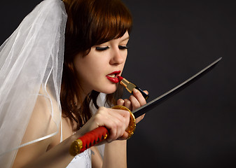 Image showing Girl lipstick looking at blade of sword