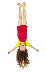 Image showing Cheerful little girl hangs upside down on white