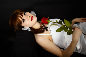 Image showing Beautiful girl with rose in hand lying on black