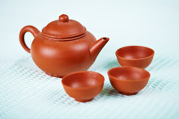 Image showing Ceramic teapot and cups on blue towel