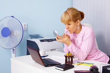 Image showing Woman adjusts makeup in office