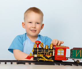 Image showing Little boy playing with a toy locomotive