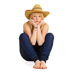 Image showing Young blonde in straw hat sitting on floor