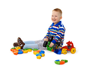 Image showing Little boy sitting among toys on floor