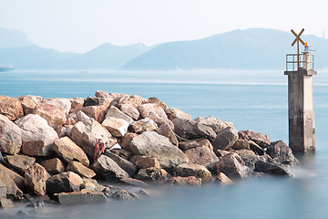 Image showing Lighthouse on a Rocky Breakwall: A small lighthouse warns of a r