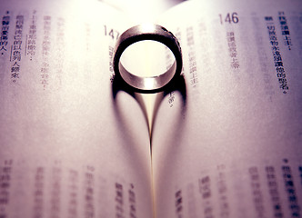 Image showing ring casts the shadow of a heart against the pages of a book 